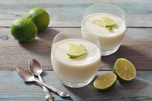 Italian dessert panna cotta with fresh lime in glass on wooden background
