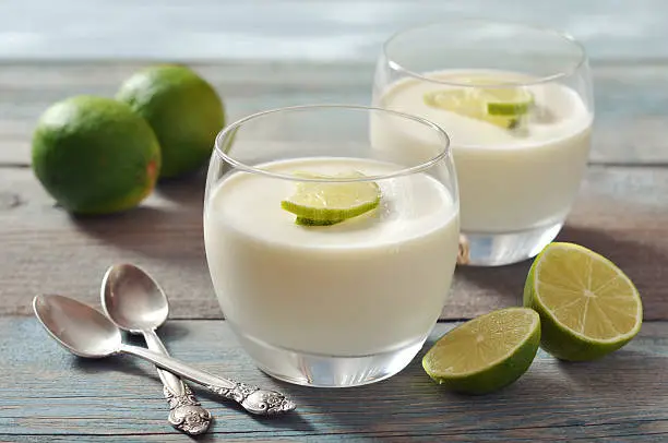 Italian dessert panna cotta with fresh lime in glass on wooden background