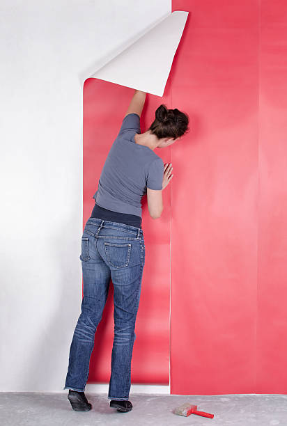 istock Woman reaching up hanging pink wallpaper 454000823
