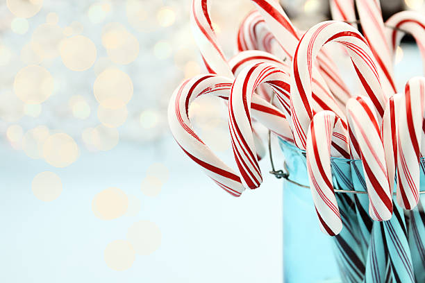 Candy Canes Against Blue Candy canes in a pretty glass blue Container. Extreme shallow depth of field with selective focus on center candy. peppermints stock pictures, royalty-free photos & images