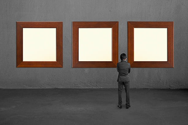 istock Businessman looking at three blank wooden frames on concrete wall 454046943