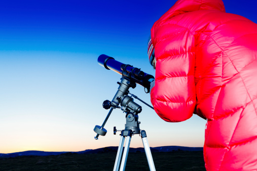 Female amateur astronomer looking through her three inch refracting telescope at sunset in readiness for an evenings skyviewing. AdobeRGB colorspace.