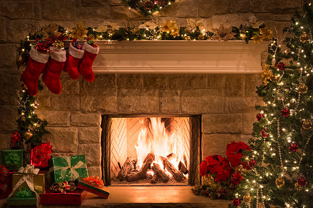 Christmas fireplace, stockings, gifts, tree, copy space Christmas tree, gifts, stockings hanging from mantel by blazing fire in fireplace. Christmas eve. fireplace stock pictures, royalty-free photos & images