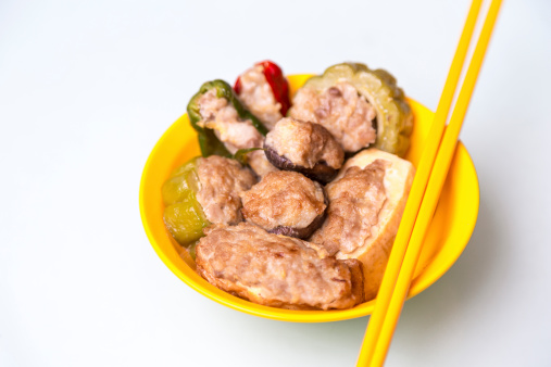 Yong Tau Fu-  Delicious Asian Chinese cuisine of fish paste stuffed on yellow bowl and white background.