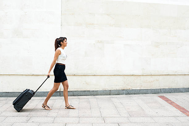 istock Young Woman Walking with Luggage on Wall Background. 454049661