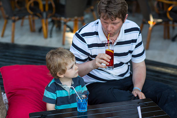istock Father and little son sitting in cafe with cocktail 454054561