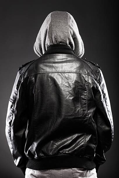 Young man in leather jacket and hood rear view Young man in leather jacket and hood rear view on back larrikin stock pictures, royalty-free photos & images