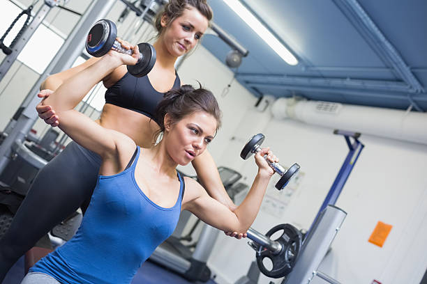 istock Focused woman lifting dumbbell weights with friend 454097267