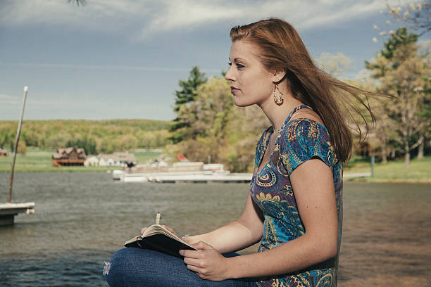 istock Young writing in a notebook by the lake 454098497
