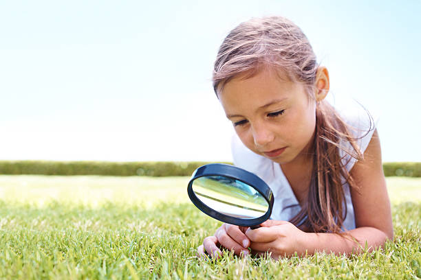 istock Girl on grass with magnifying glass 454099401