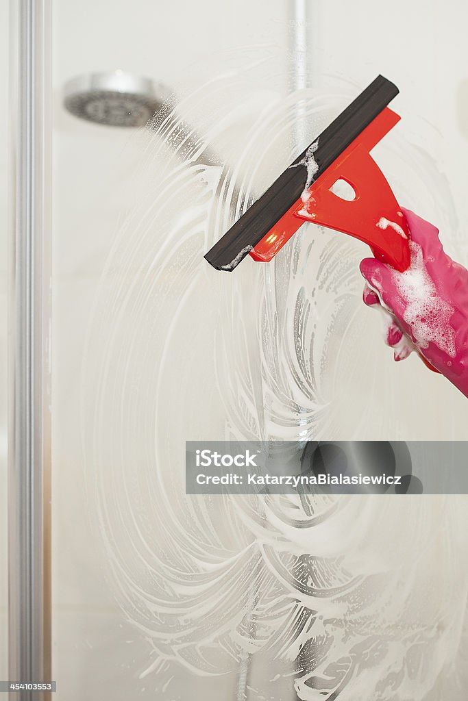 Shower cleaner A man with a glove cleaning a shower with a window cleaner Shower Stock Photo