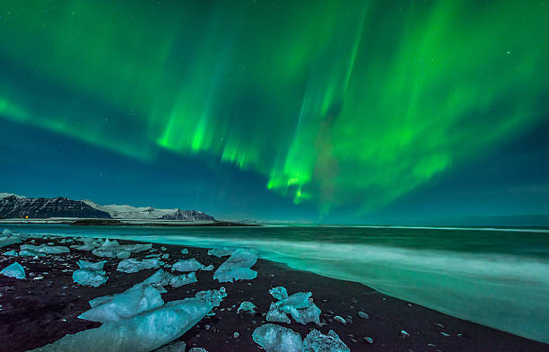 Aurora over Ice Beach A beautiful aurora display over the ice beach near Jokulsarlon, Iceland. iceberg dramatic sky wintry landscape mountain stock pictures, royalty-free photos & images