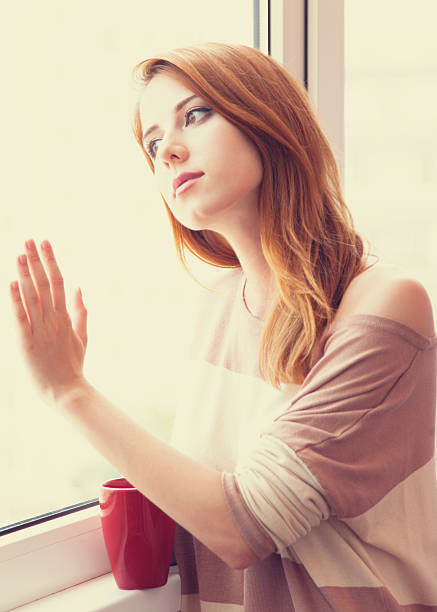 istock Beautiful young woman with cup over window. 454125087
