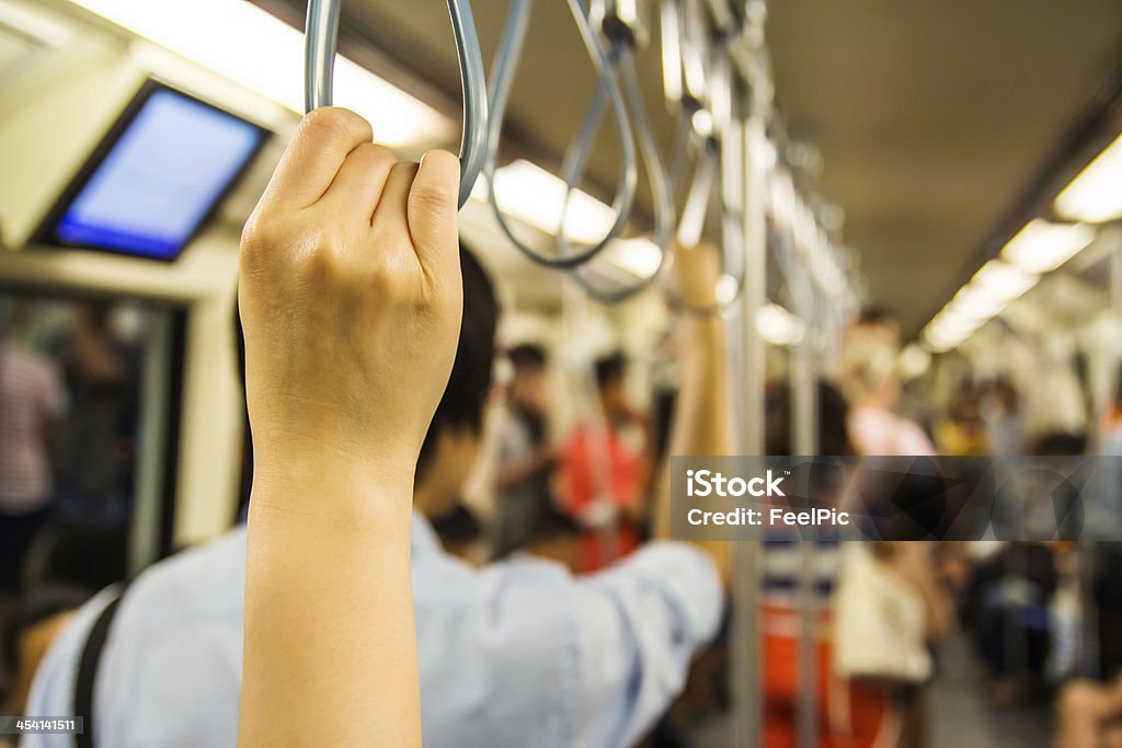 Woman holding onto a handle Woman holding onto a handle on a train Gripping Stock Photo
