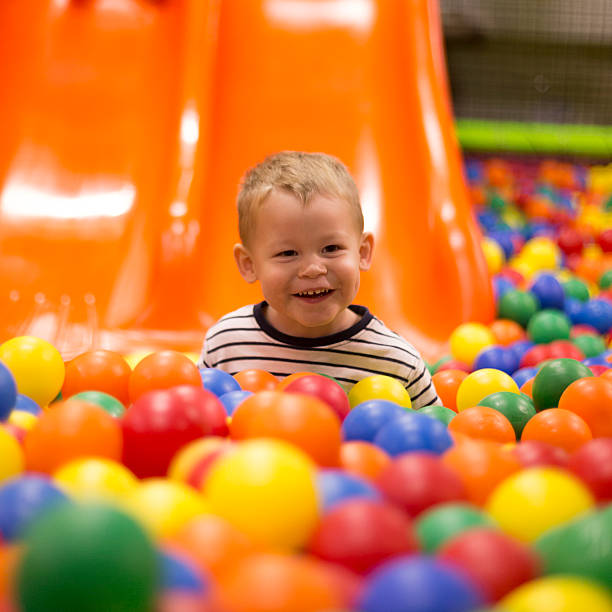 Young boy smiling in bright, multicolor ball pit stock photo