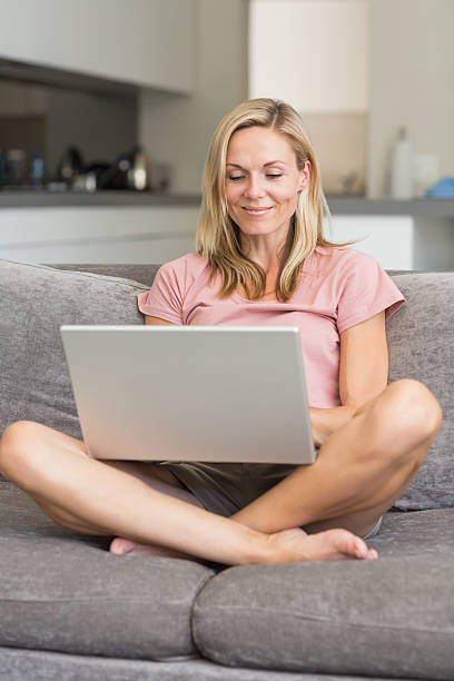 istock Happy mature woman using laptop on sofa 454141995