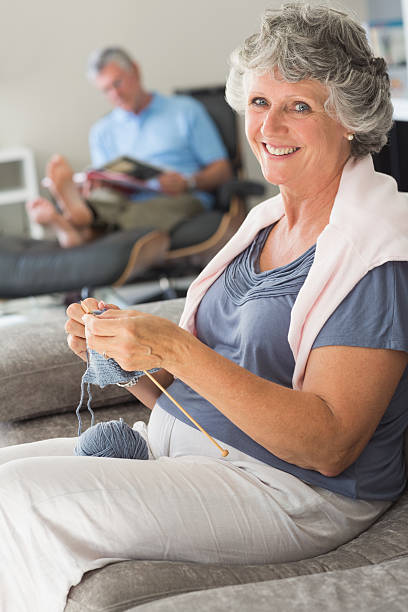 istock Happy mature woman knitting while her husband is reading 454142461