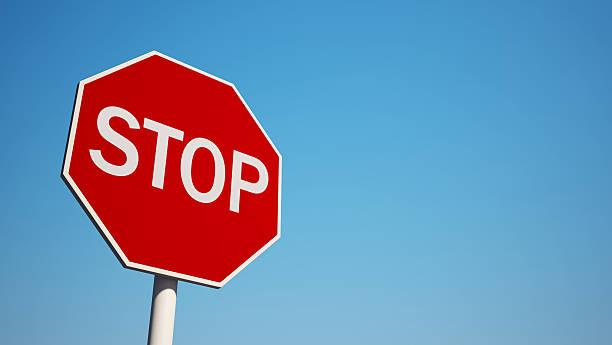 Photo of a stop sign with blue sky background Stop Sign isolated on clean blue sky stop stock pictures, royalty-free photos & images