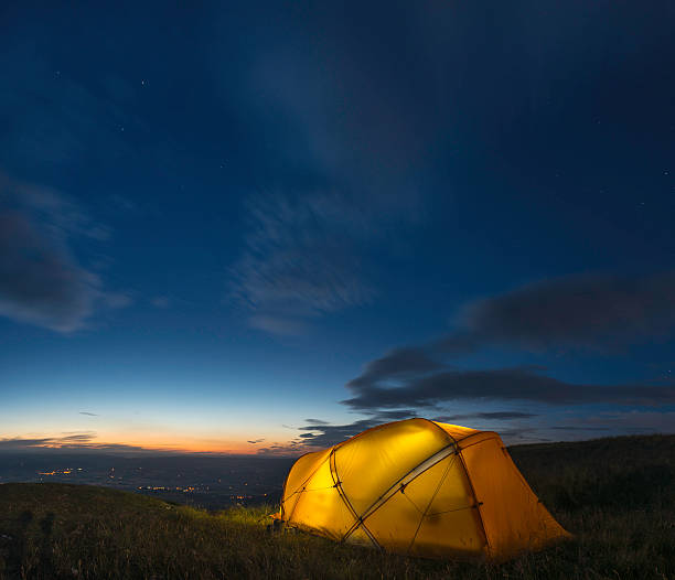 istock Yellow dome tent illuminated beneath chrome blue starry sky 454148069