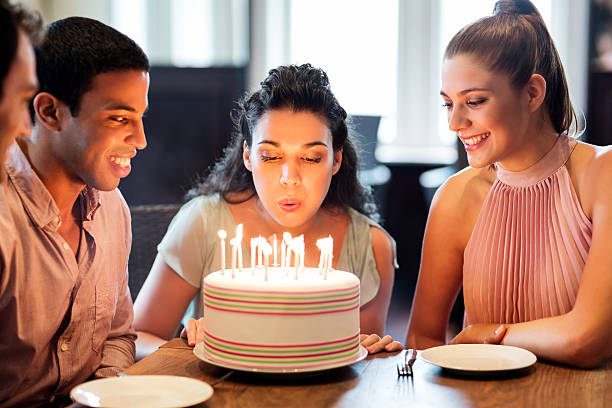istock Woman Blowing Candles On Cake With Friends 454153749