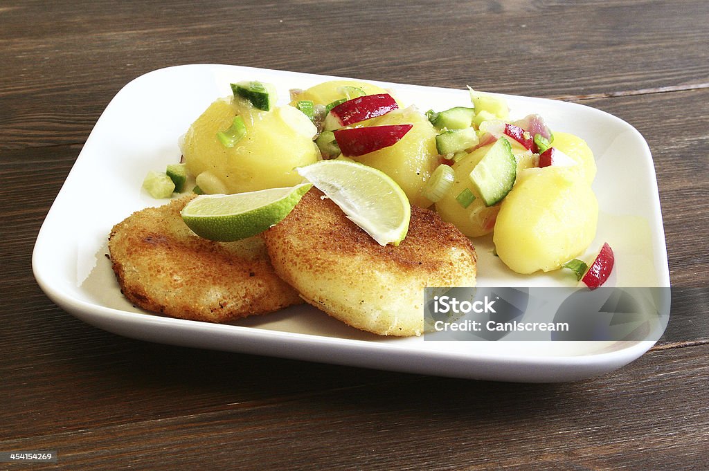 Schnitzel with Potato Salad Kohlrabi-schnitzel with a wasabi potato salad and cut lime on a white plate. Boiled Potato Stock Photo