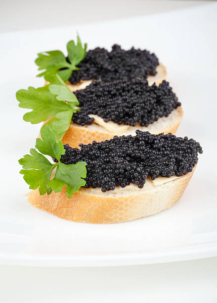 istock Small sandwiches with black caviar on white plate 454163897