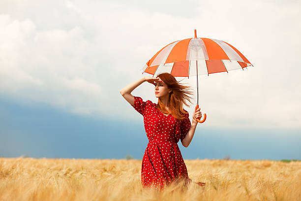 istock Redhead girl with umbrella at field 454165683