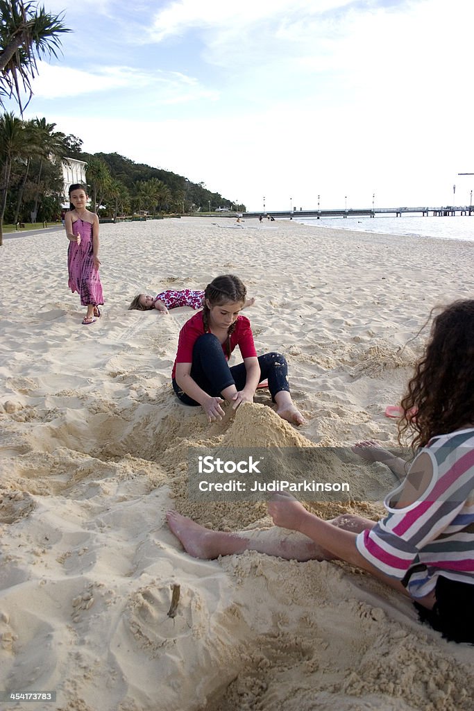 Bambini che giocano con la sabbia in spiaggia - Foto stock royalty-free di Adolescente