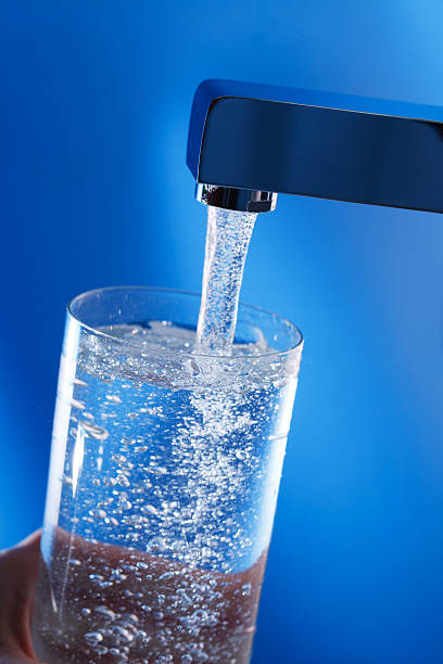 istock Filling up a glass of water . Blue background. 454174377