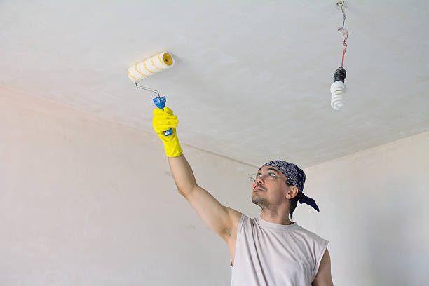 Cтоковое фото Молодой работник картина с валиком потолка