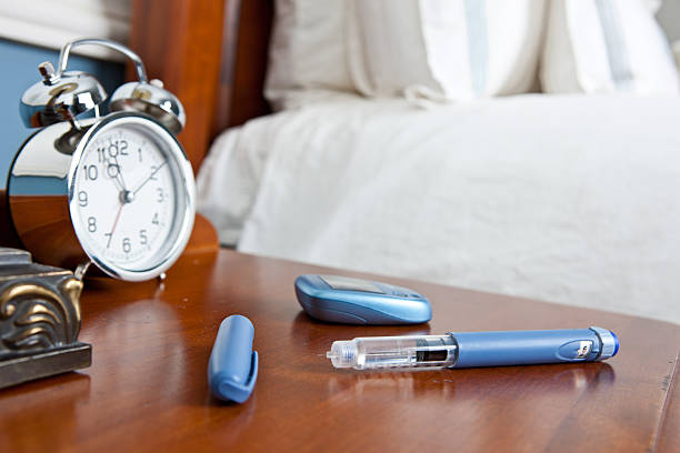 Insulin Pen and Glucometer on Night Stand stock photo