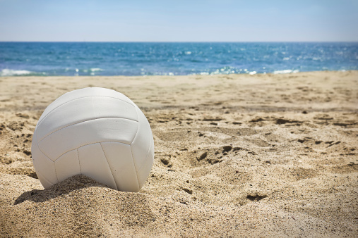 White volleyball sits on top of the sand.