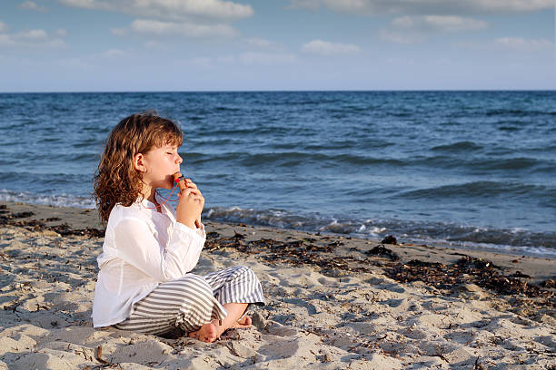 istock little girl play pan pipe on beach 454179741