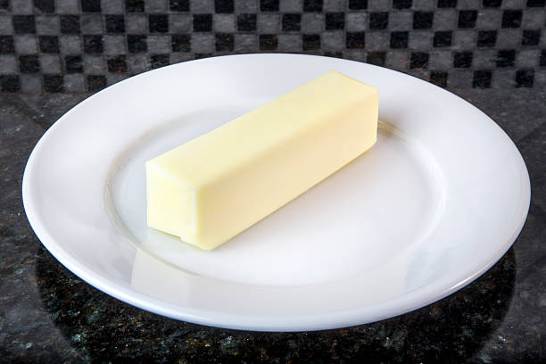Butter A kitchen plate with a stick of butter, sitting on top of a granite counter top. STICK OF BUTTER stock pictures, royalty-free photos & images