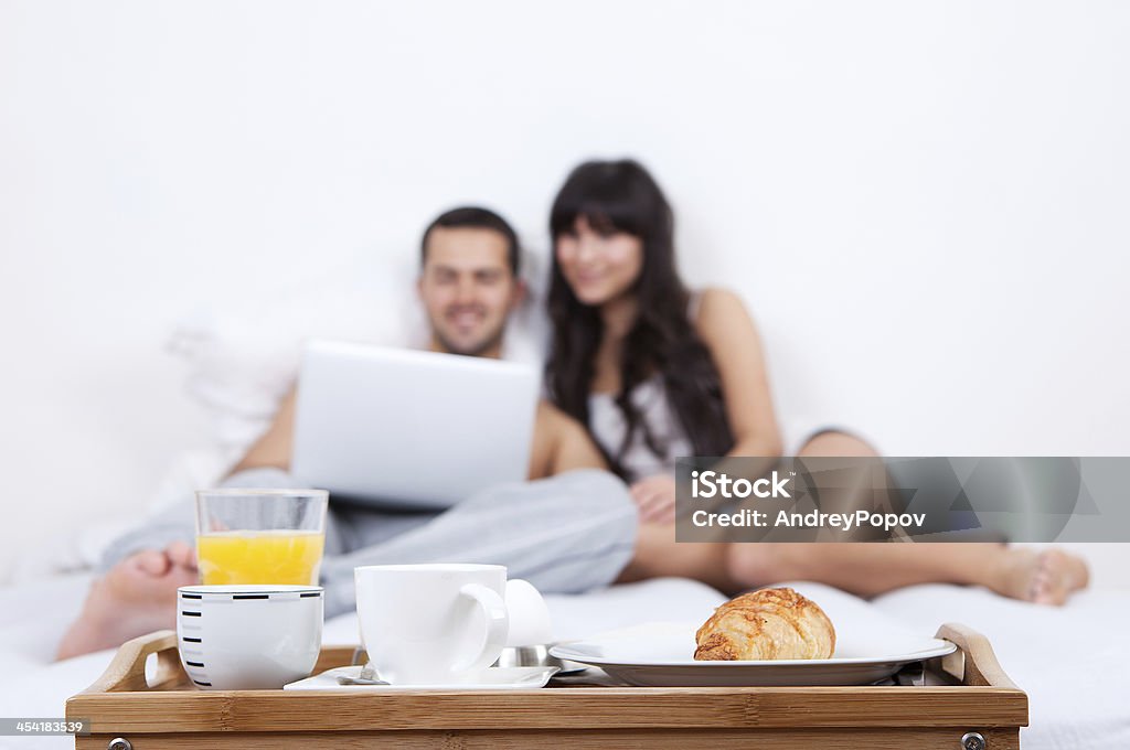 Pareja joven yacer en la cama con la computadora portátil - Foto de stock de Acostado libre de derechos