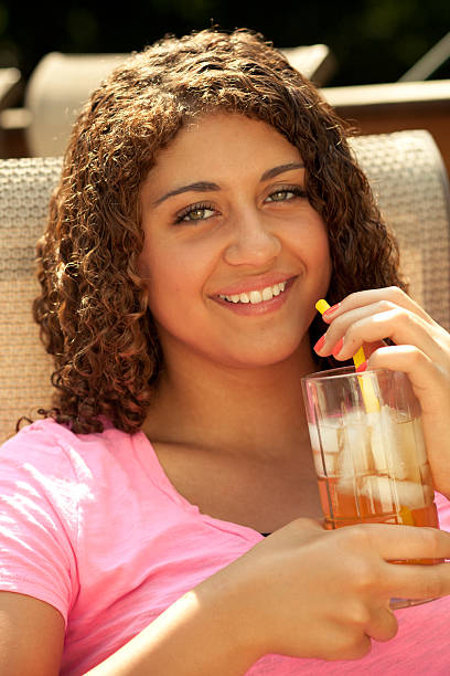 Beautiful teen girl smiling with iced beverage on summer day stock photo