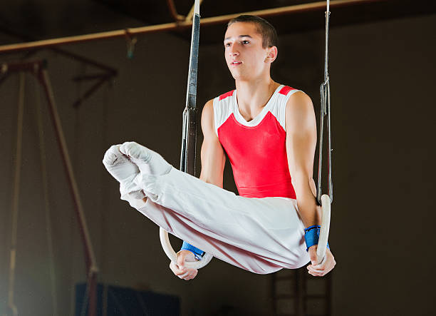 Man working out on gymnastic rings. Young man doing difficult exercises on gymnastic rings.   artistic gymnastics stock pictures, royalty-free photos & images