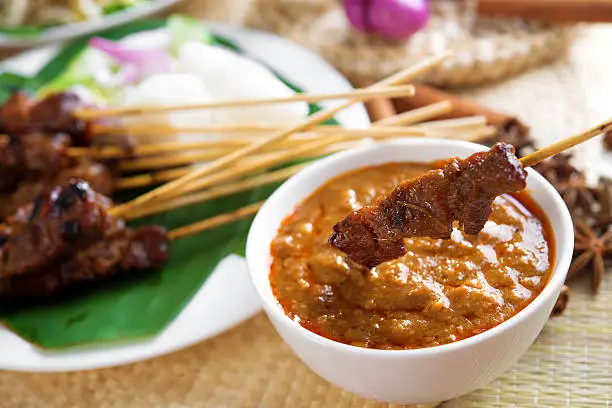 Satay or sate, skewered and grilled meat, served with peanut sauce, cucumber and ketupat. Traditional Malay food. Malaysian dish, Asian cuisine.