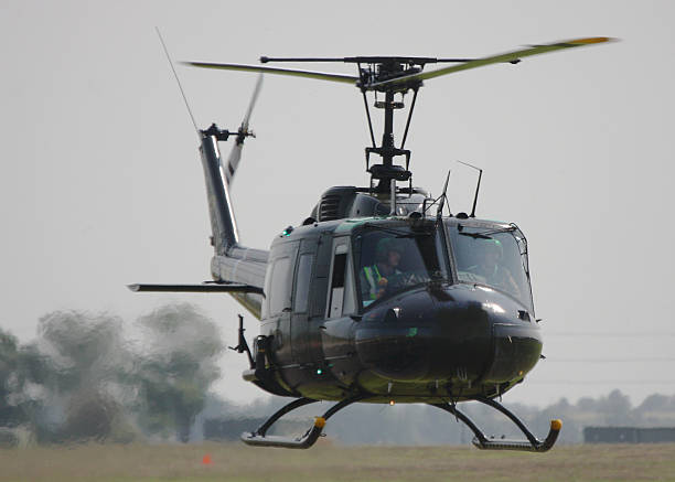 Bell UH-1H - Vietnam veteran Huey A Bell UH-1H Iroquois military helicopter - a veteran of the Vietnam War - hovers close to the ground in a thick heat haze. Green grass and  trees are visible through haze generated by the weather and by the chopper's jet exhaust. uh 1 helicopter stock pictures, royalty-free photos & images