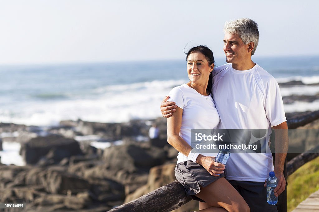 mature couple relaxing after exercise happy mature couple relaxing after exercise at the beach Active Lifestyle Stock Photo