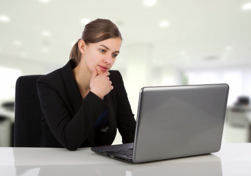 Attractive business woman looking at her laptop screen in an office environment