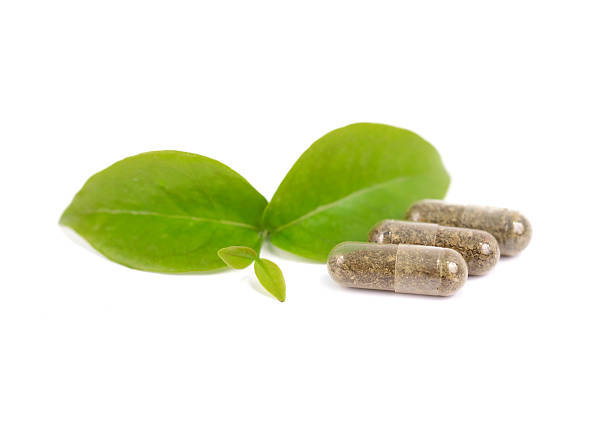 herbal medicine pills with green plant on white background stock photo