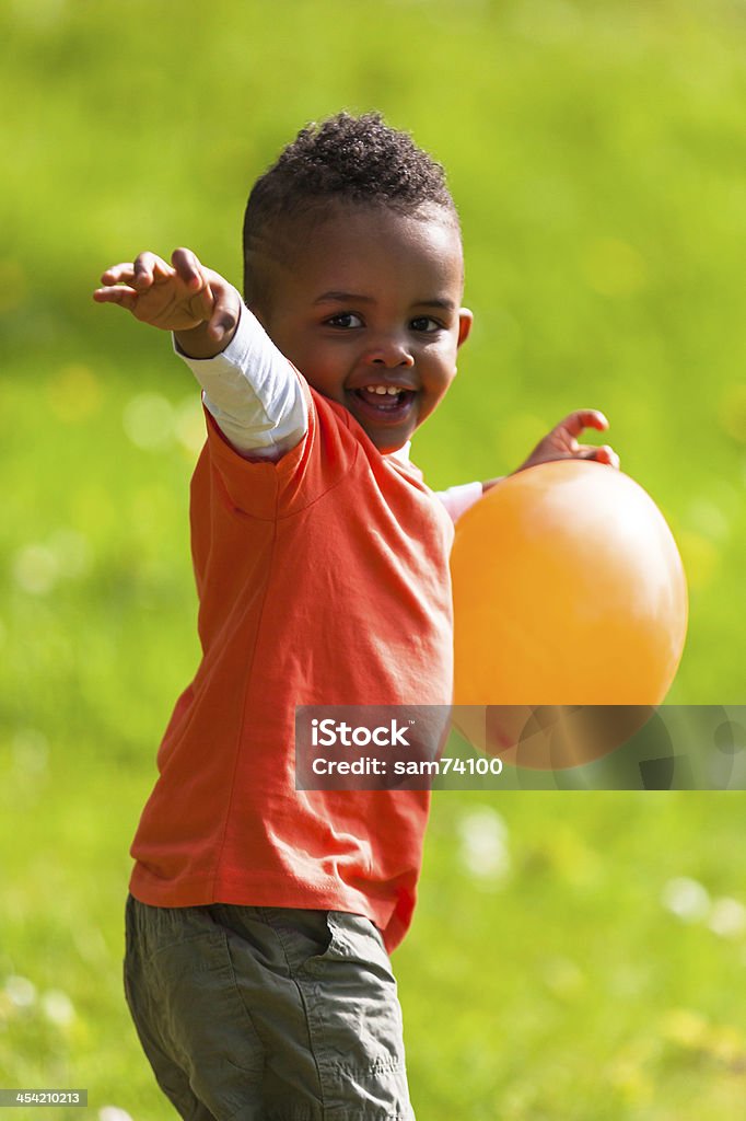 Outdoor portrait of a cute young  little black boy playing Outdoor portrait of a cute young  little black boy playing with a balloon - African people African Ethnicity Stock Photo