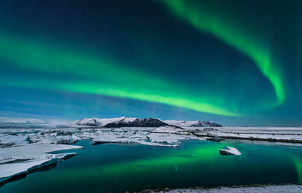 Aurora over Lagoon The Northern Lights dance over the glacier lagoon in Iceland. iceberg dramatic sky wintry landscape mountain stock pictures, royalty-free photos & images