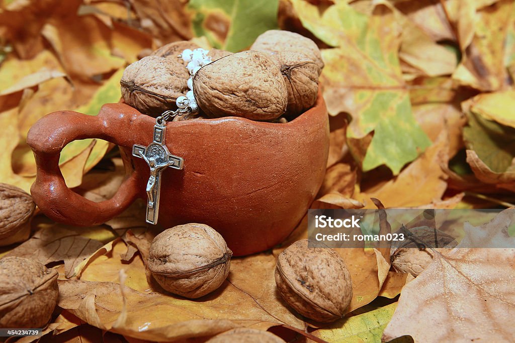 religious autumn detail Nuts spilled from ceramic pot on background autumn leaves Antioxidant Stock Photo