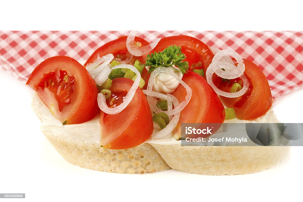 Open sandwich with tomatoes and onion Open faced sandwich with sliced tomatoes and onion on napkin. Decorated with parsley. White background, selective focus, shallow DOF. Appetizer Stock Photo