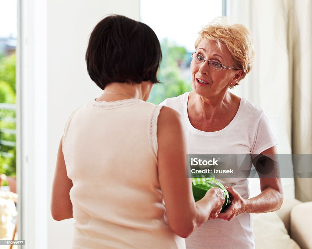 Birthday gift Mature woman handing a gift to her friend.  Gift Stock Photo