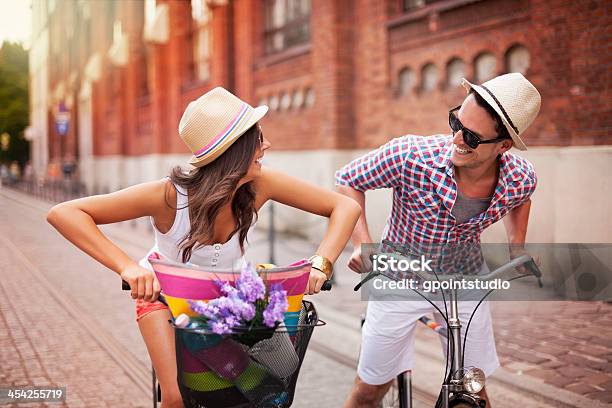 Happy Couple Chasing On Bike In The Street Stock Photo - Download Image Now - Cycling, Young Couple, Activity