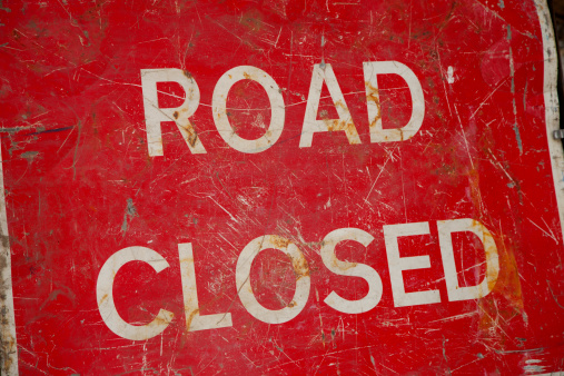 Close up shot of a battered red Road Closed sign.