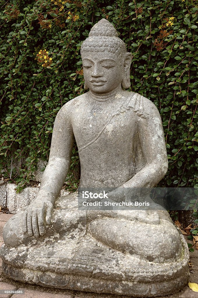 Stone Buddha in the lotus position. Stone Buddha sitting in lotus position in the garden. Adult Stock Photo
